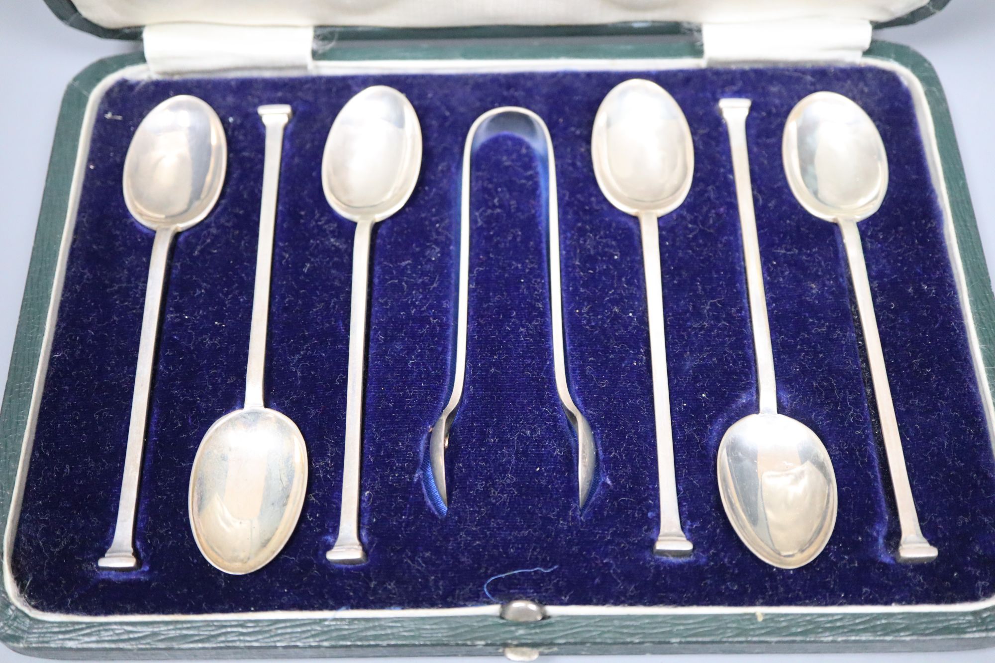 A collection of small silver to include a cased set of six coffee spoons and tongs, three wine labels and a pair of grape scissors